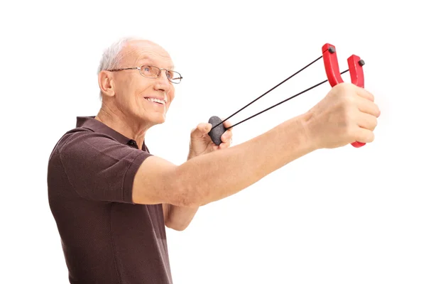 Vrolijke senior man schieten een katapult — Stockfoto