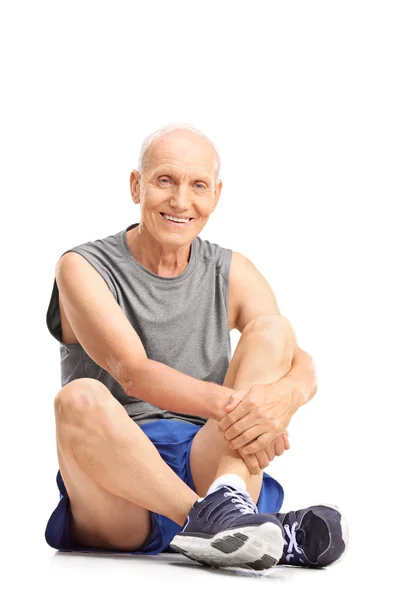 Старший мужчина в спортивной одежде сидит на полу — стоковое фото