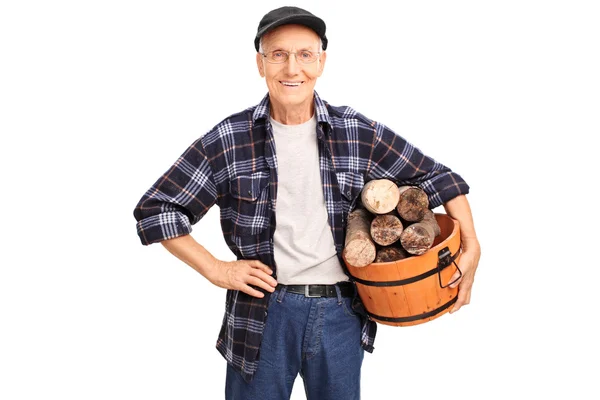 Senior mholding una cesta llena de troncos — Foto de Stock