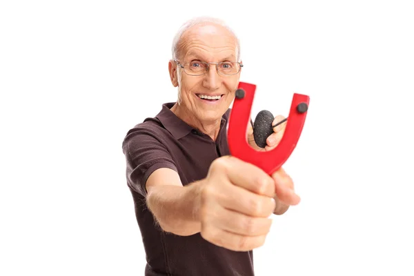 Cheerful senior gentleman shooting a slingshot — Stock Photo, Image