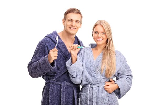 Couple in blue bathrobes holding toothbrushes — Stock Photo, Image