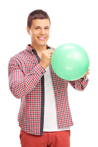 Giovane uomo che fa esplodere un palloncino verde — Foto Stock