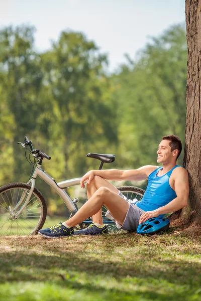 Young cyclist sitting in park — Stock Photo, Image