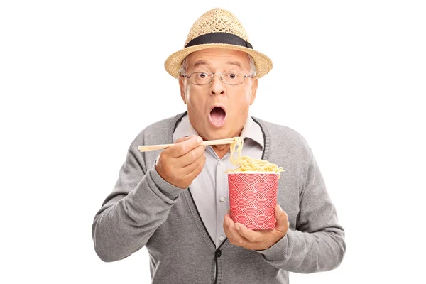 Senior gentleman eating Chinese food with sticks — Stok fotoğraf