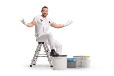 Beyaz arka planda izole edilmiş boya kovalarıyla merdivende oturan neşeli bir ressam.