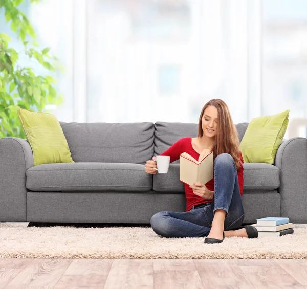 Vrouw lezen van een boek en drinken koffie — Stockfoto