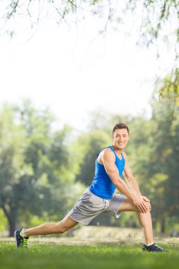 Athlete doing stretching exercises in a park