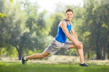 Athlete doing stretching exercises in a park
