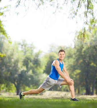 Young athlete stretching his legs in a park
