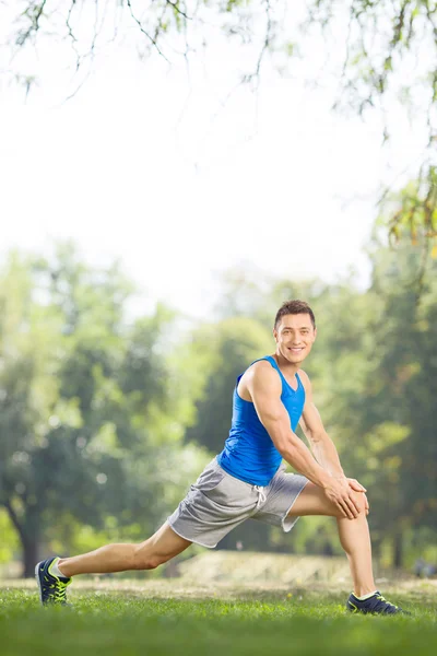 Atleta che fa esercizi di stretching in un parco — Foto Stock