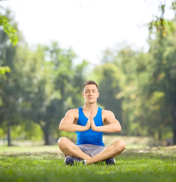 Junge Athletin sitzt auf Gras und meditiert — Stockfoto