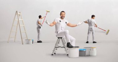 Ressamlardan oluşan bir ekip bir odada duvar boyuyor.