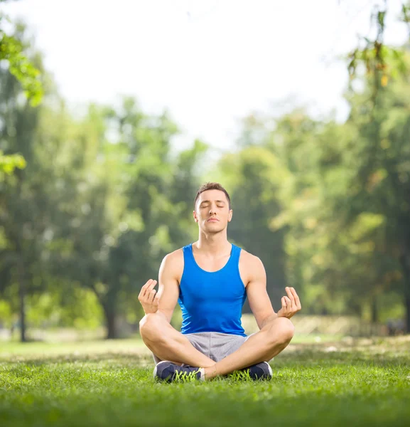 Giovane uomo che pratica yoga in un parco — Foto Stock