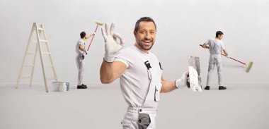 Bir odada çalışan neşeli ressamlar ve duvar işçilerinden oluşan bir ekip.