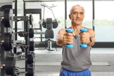 Son sınıf öğrencisi spor salonunda dambıllarla egzersiz yapıyor.