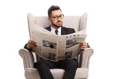 Siyah takım elbiseli bir adam beyaz arka planda izole edilmiş bir gazete okuyor.