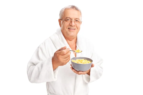 Anziano in accappatoio mangiare cereali — Foto Stock