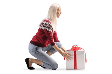 Genç bir kadın beyaz arka planda izole bir şekilde yere hediye bırakıyor. 