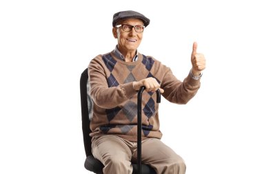 Sandalyede oturan yaşlı bir adam, beyaz arka planda izole bir şekilde baş parmak işareti yapıyor.