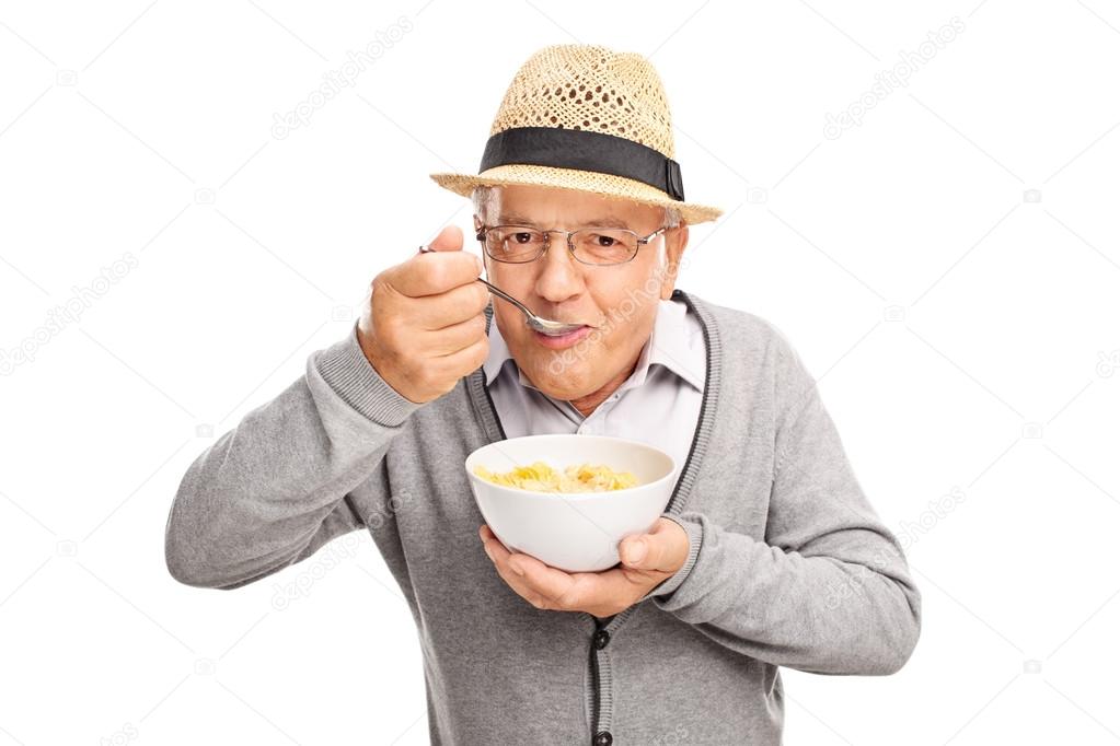 Senior man eating cereal with a spoon