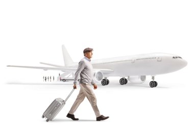 Havaalanında yürüyen ve beyaz arka planda izole edilmiş bir bavulu çeken yaşlı bir beyefendinin tam boy profil fotoğrafı.