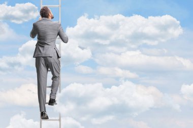Gri takım elbiseli bir işadamının gökyüzünde merdivene tırmanırken görüntüsü.