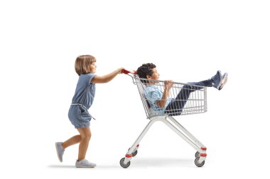 Küçük bir kızın beyaz arka planda izole edilmiş alışveriş arabasında küçük bir çocuğu iterken uzun bir profil fotoğrafı.