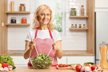 Kadın mutfakta salata yapıyor.