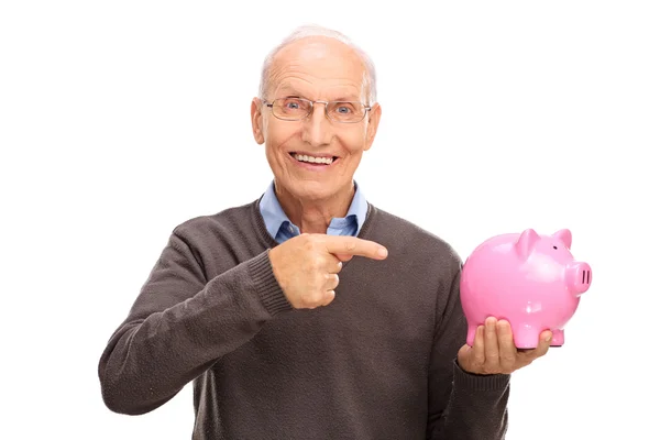 Senior man pointing towards a piggybank — Stock Photo, Image