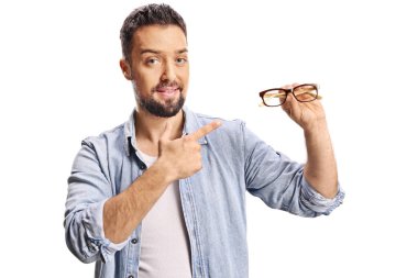 Genç adam beyaz arka planda izole edilmiş bir çift gözlüğe işaret ediyor.