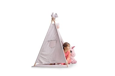 Beyaz arka planda pembe bir tek boynuzlu at oyuncağıyla çadırda oturan genç bir kız.