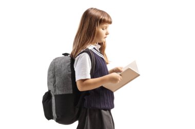 Üniformalı kız öğrenci beyaz arka planda izole edilmiş bir kitap okuyor ve yürüyor.