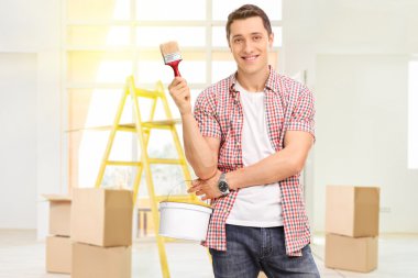 Man holding a paintbrush and a color bucket