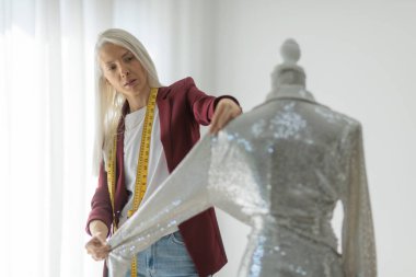 Moda tasarımcısı stüdyoda pullu bir elbise üzerinde çalışıyor.