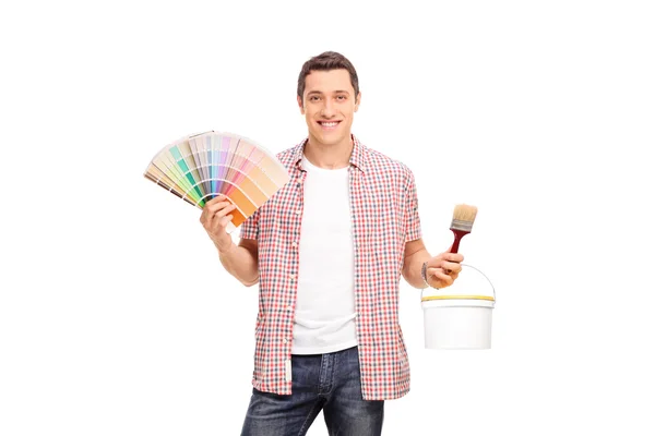 Man holding color swatch and a paintbrush — Stock Photo, Image