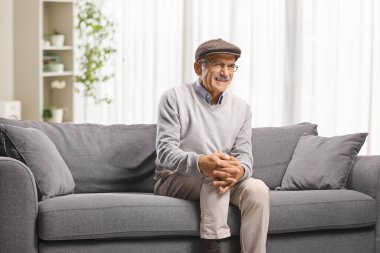 Kanepede diz ağrısı çeken yaşlı bir adam.