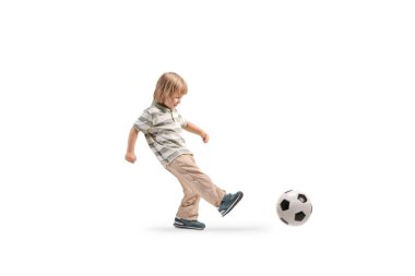 Genç bir çocuk beyaz arka planda top oynuyor ve tekmeliyor.