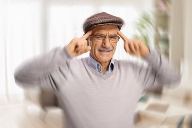 Baş ağrısı ve baş dönmesinden muzdarip yaşlı adamın parmakları şakaklarında.