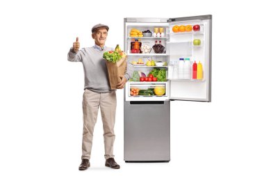 Beyaz arka planda izole edilmiş buzdolabının yanında duran son sınıf öğrencisi.