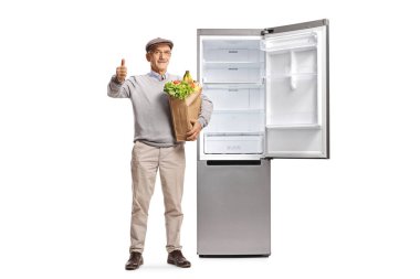 Üst düzey bir adam boş bir buzdolabının önünde elinde alışveriş torbasıyla dikiliyor.