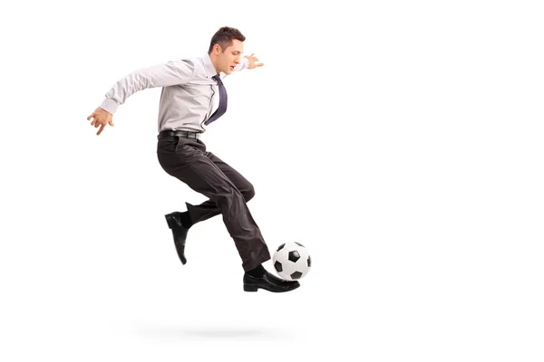 Young businessman kicking a football — Stockfoto