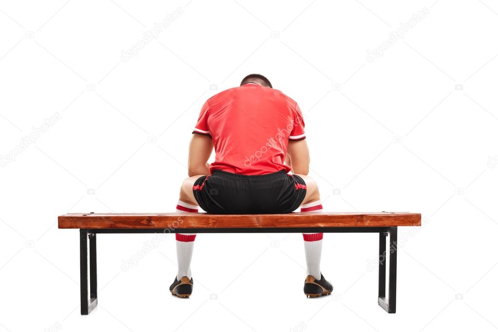 Sad football player sitting on bench