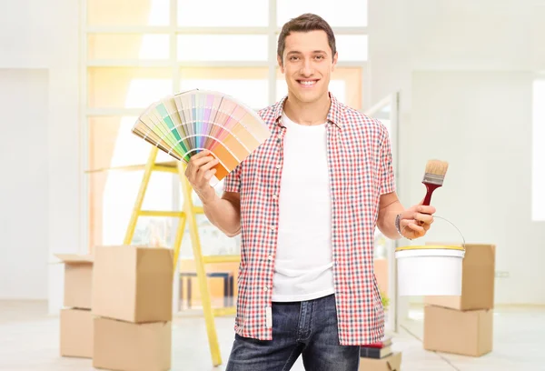 Man holding a paintbrush and a color swatch — Stock Photo, Image