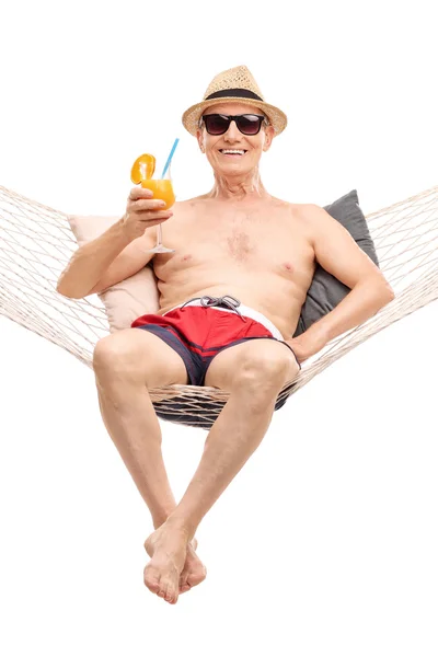 Senior man in een hangmat drinken een cocktail — Stockfoto