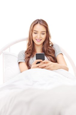 Woman lying in bed and typing on phone