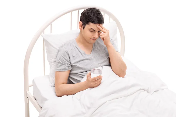 Man lying in a bed and experiencing a headache — ストック写真