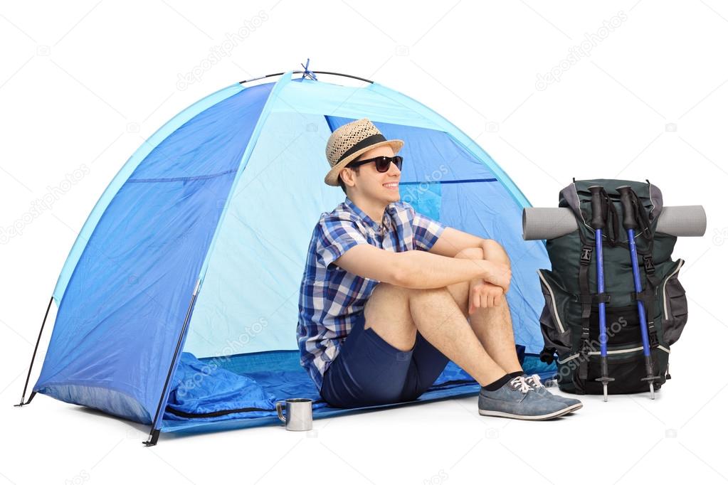male hiker sitting in front of a tent