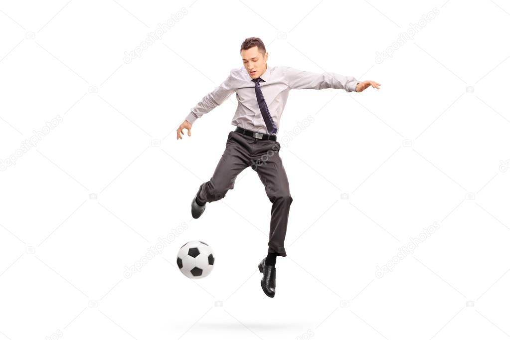 Young businessperson kicking a football