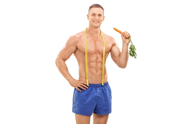 Young male athlete holding a carrot — Stockfoto