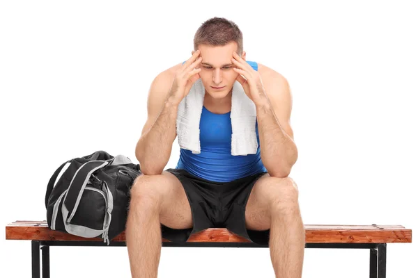 Sad athlete sitting on a bench — Stock Photo, Image